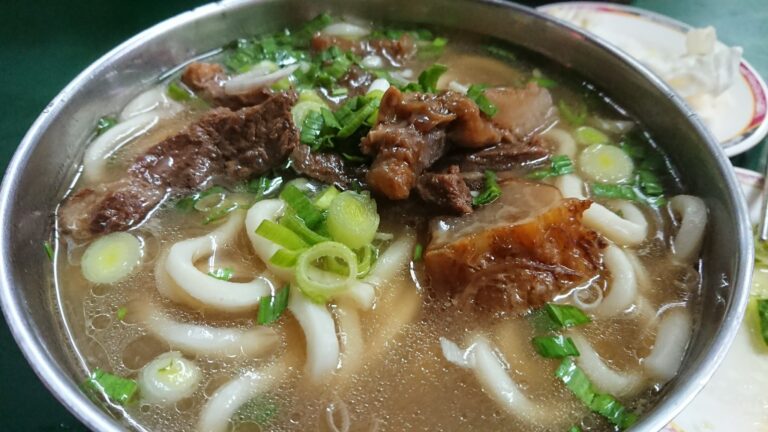 Taiwan beef noodle soup with clear broth, beef chunks, and scallions