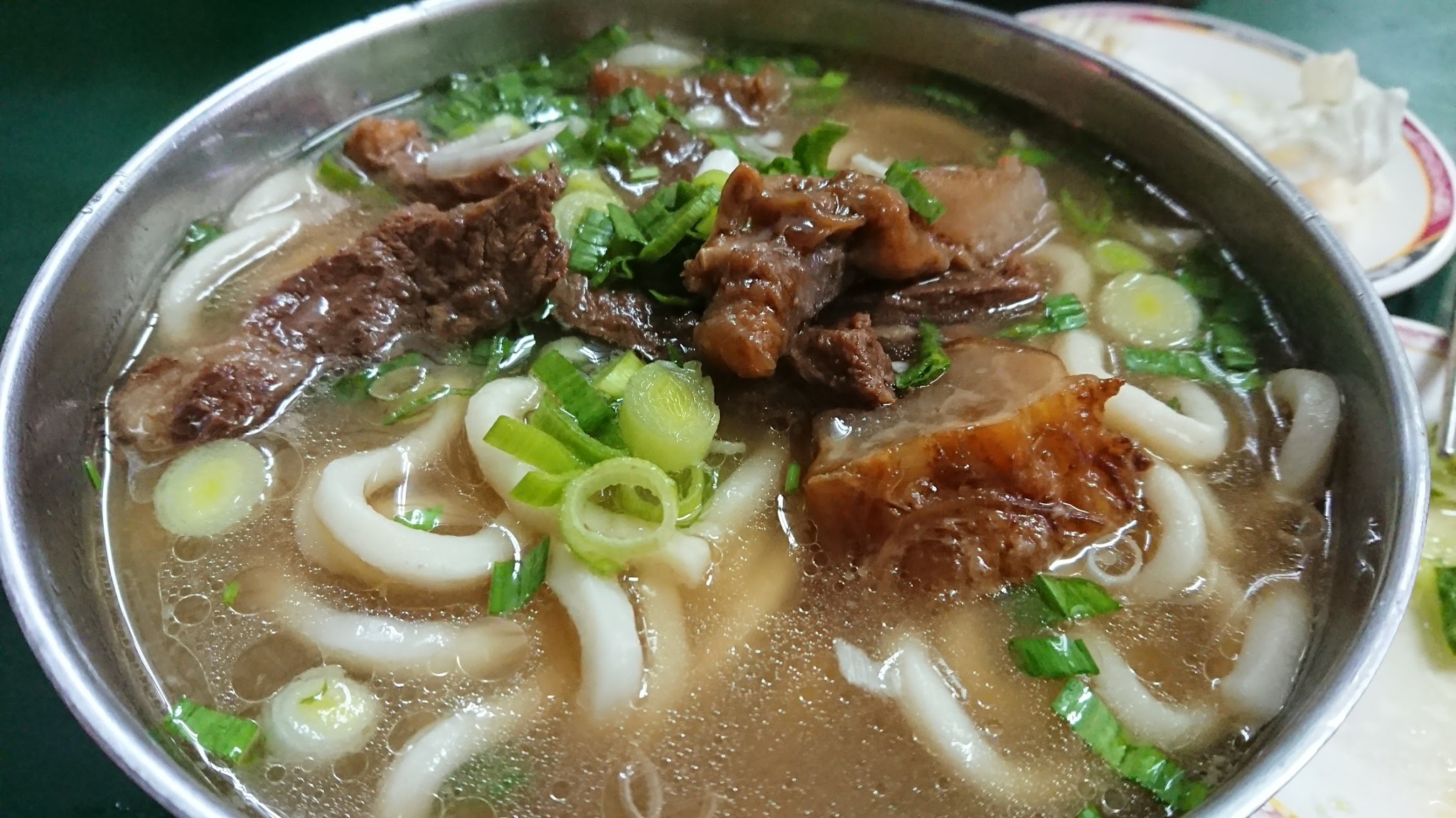 Taiwan beef noodle soup with clear broth, beef chunks, and scallions