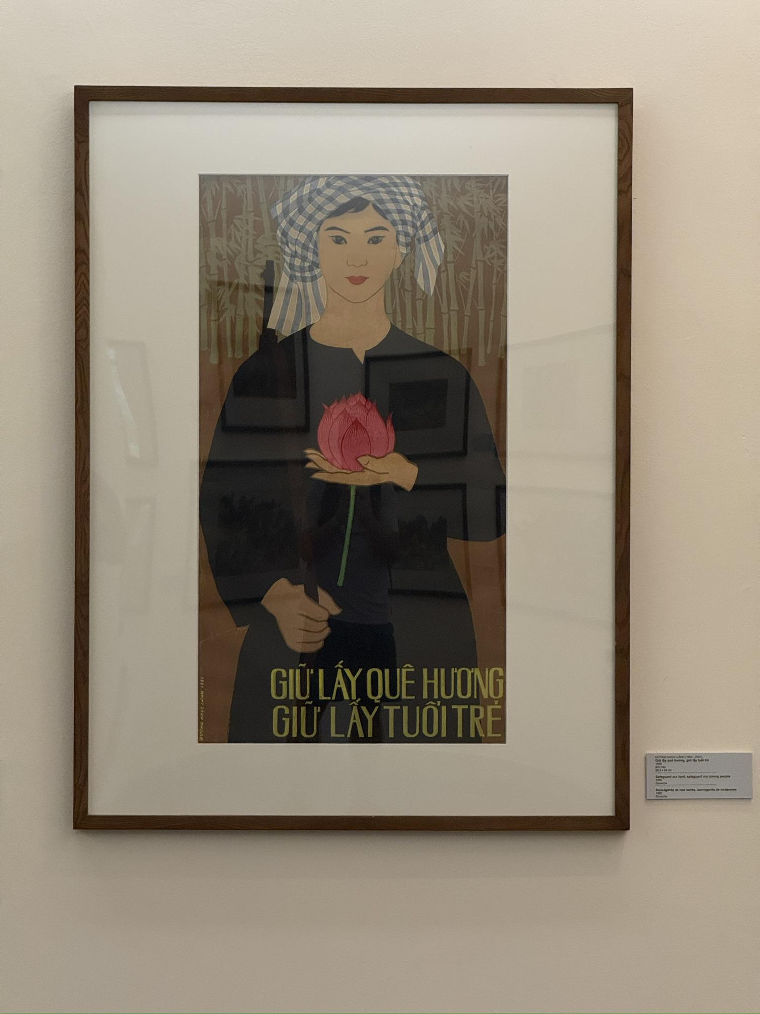 Vietnam War propaganda poster depicting a woman holding a lotus flower in one hand and a rifle in the other, taken at Vietnam National Museum of Fine Arts