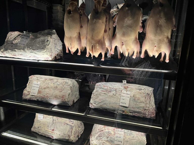 熟成櫃裡的鴨與牛，靜靜掛著、躺著，等待時間替它們完成最後一道信任儀式。沒有標籤能取代這段漫長的熟成，也沒有演算法能複製那股越陳越深的氣味。這正是人類信任真正的樣子——被時間反覆驗證過的角色穩定度。