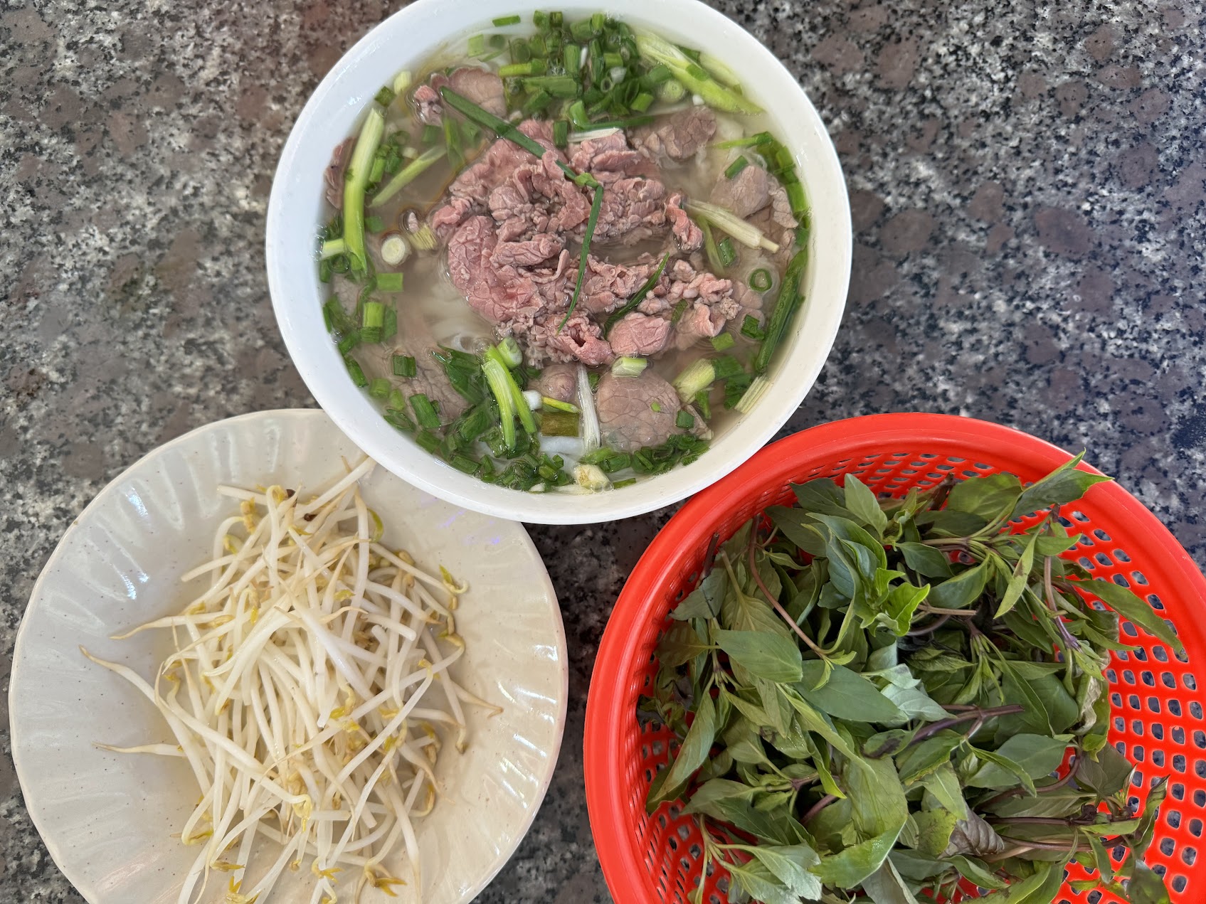 澄んだスープの牛肉麺に、もやしと香草が添えられた一杯。スープ、でんぷん、肉、追加の口当たりが一緒に働く構造が見える。