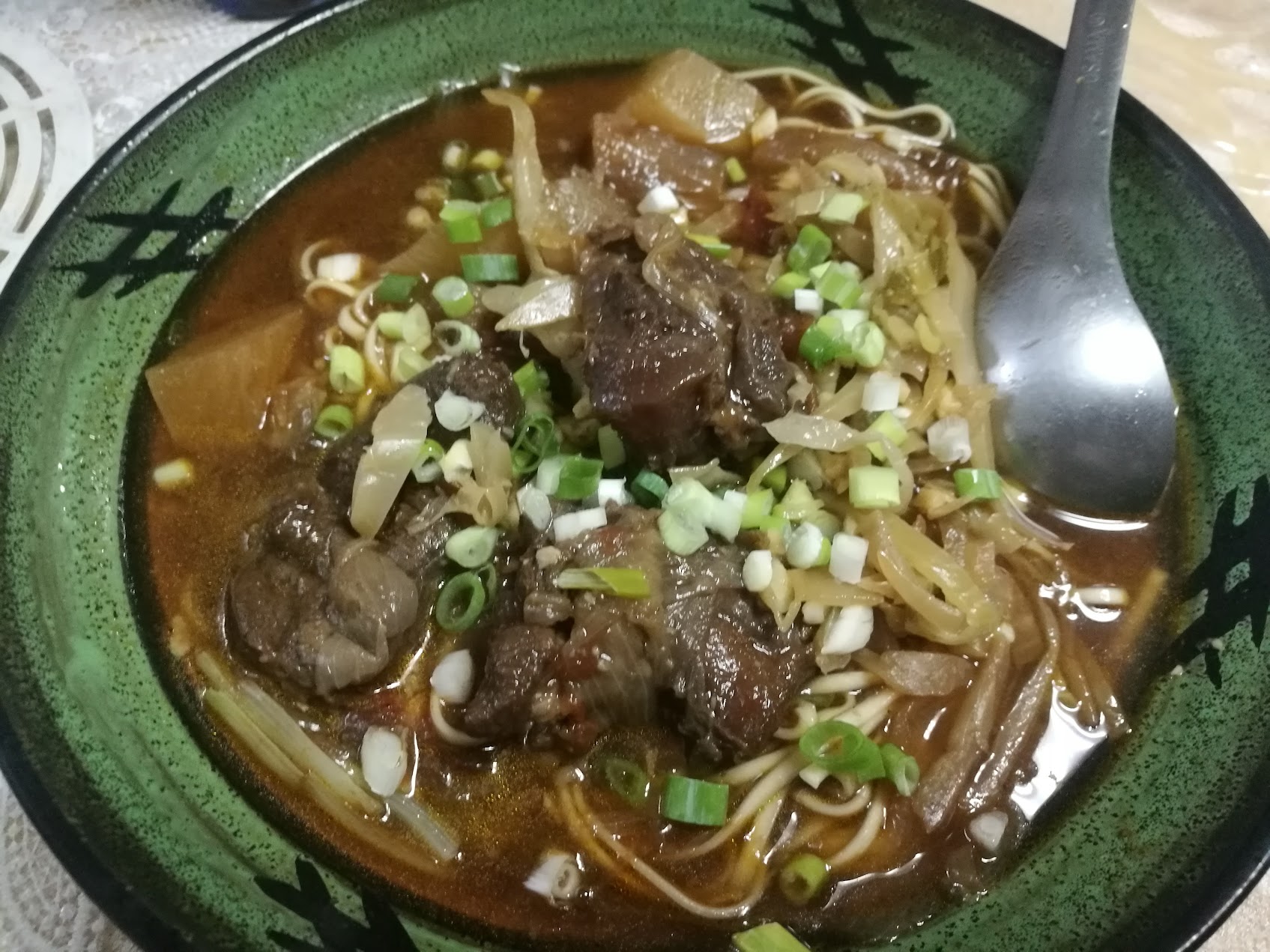 濃い色のスープに牛肉、酸菜、青菜、麺が入った台湾の紅焼き牛肉麺。
