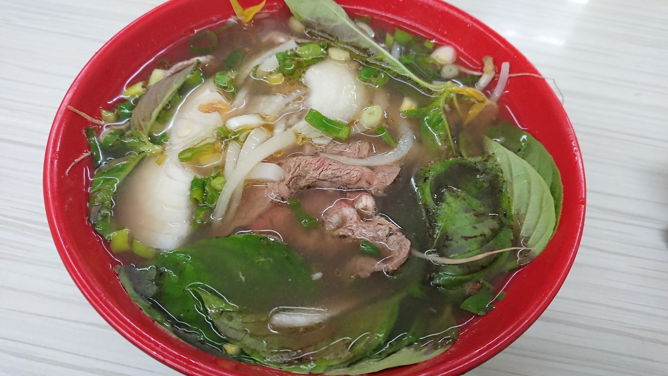 澄んだスープのフォー。バジル、青ねぎ、玉ねぎ、牛肉がのり、透明感のあるスープ構造が見える。