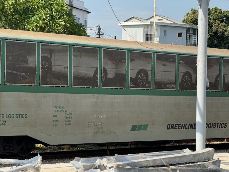 越南鐵路場站中載運汽車的物流車廂，呈現中國電動車、鐵路運輸與東南亞供應鏈接軌的現場。
