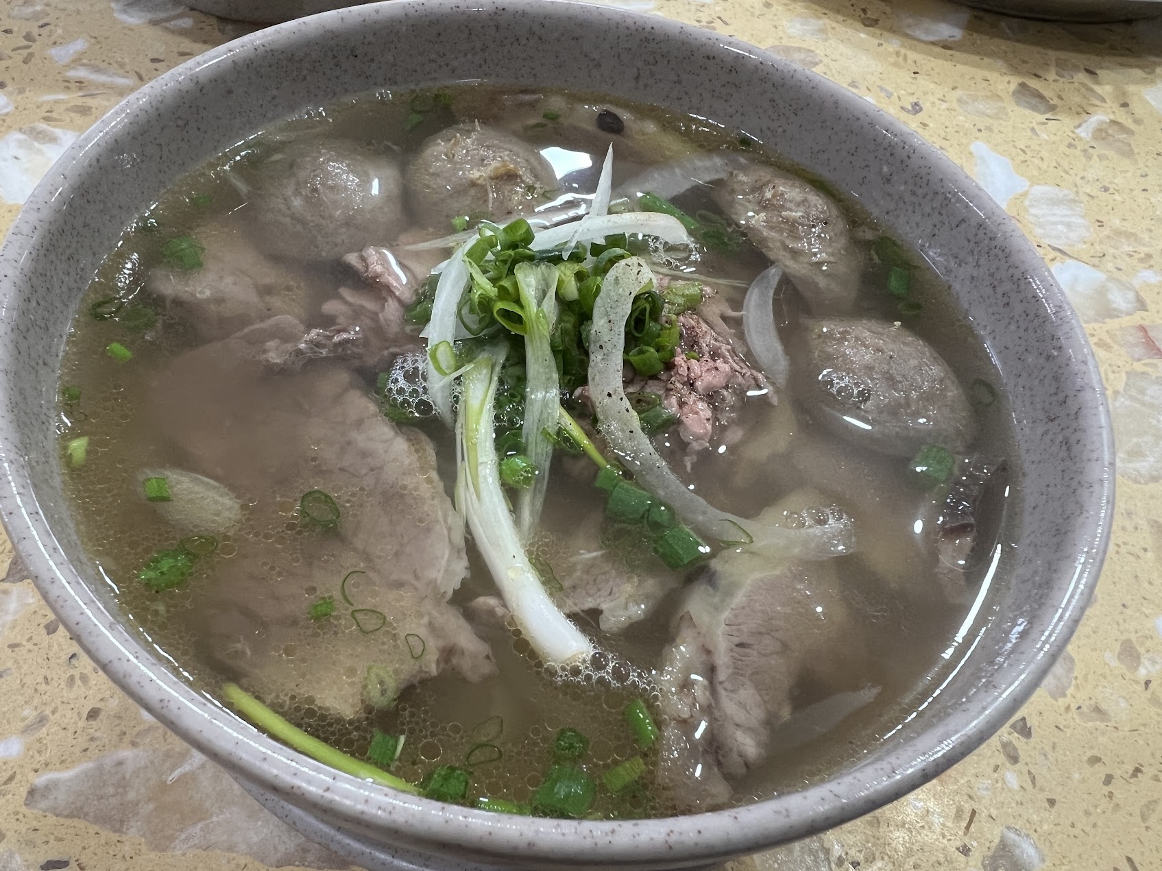 牛肉、牛肉団子、青ねぎ、玉ねぎをのせた、ハノイ風の澄んだ牛肉フォー。北部ベトナムのフォーの清い輪郭がよく見える。