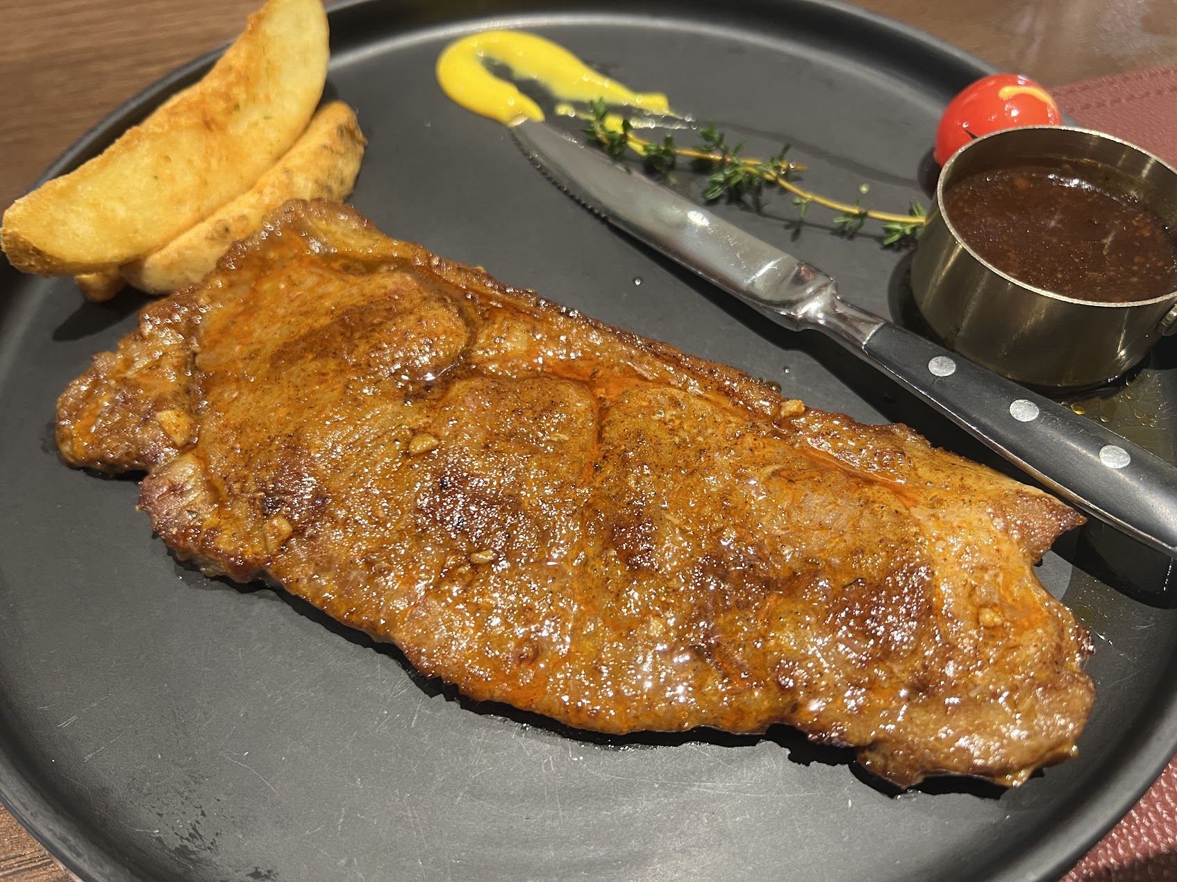 中露国境の黒河で食べたロシア風ステーキ。黒い皿にポテト、ソース、ハーブとともに盛られ、国境都市ならではのローカルなステーキの表情が見える。