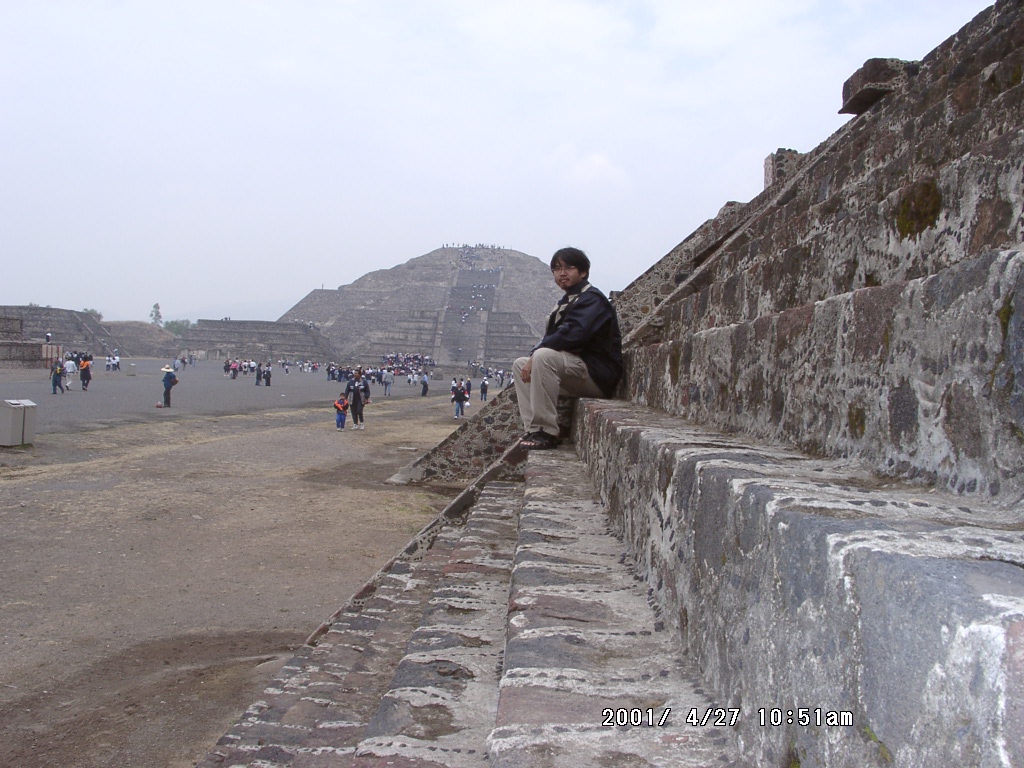 2001年、テオティワカン遺跡で石段のそばに座る周端政。遠くに大きなピラミッドが見える。