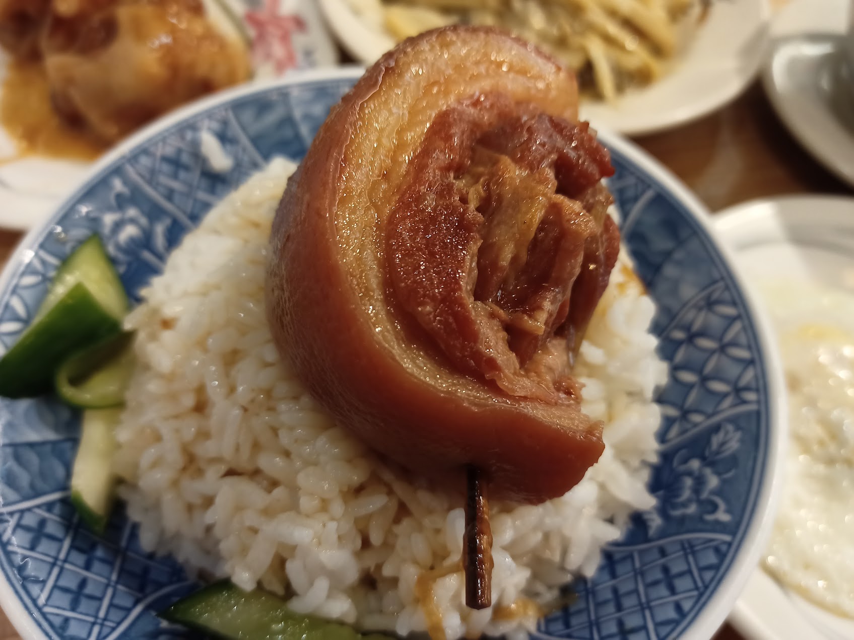 青い模様の碗のご飯の上に、皮と脂を残した大きな煮込み豚肉がのった一杯。爌肉飯に近い肉の存在感を示している。