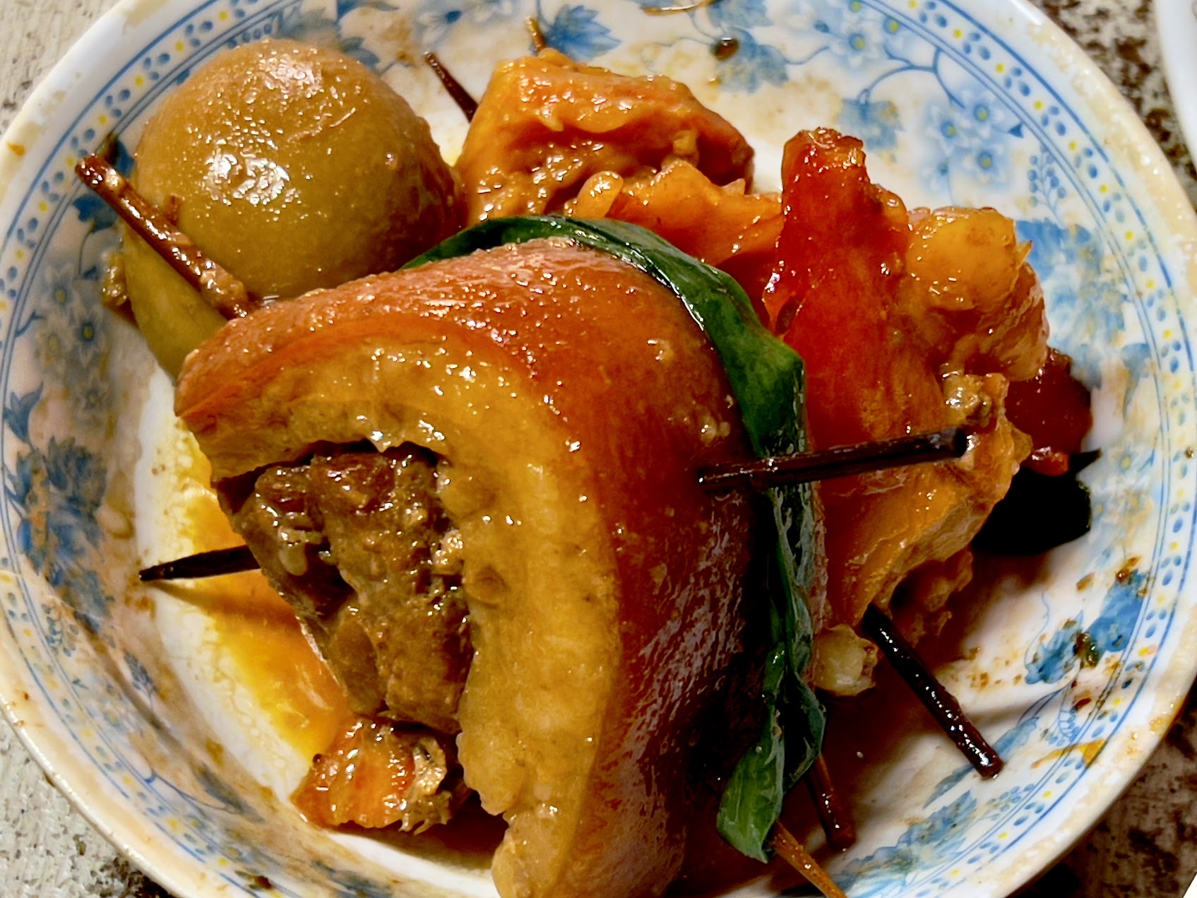 一碗白飯上放著大塊滷豬肉與滷蛋，旁邊可見醃菜與清炒蔬菜。