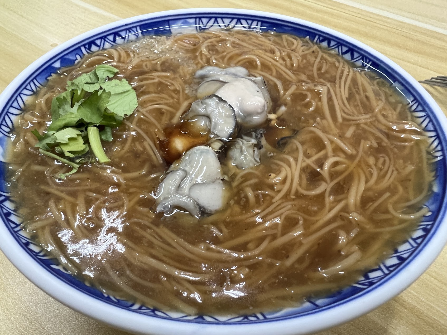 台湾の蚵仔麵線の一碗。薄いとろみのある褐色の湯が紅麵線を包み、上に蚵仔と香菜がのっている