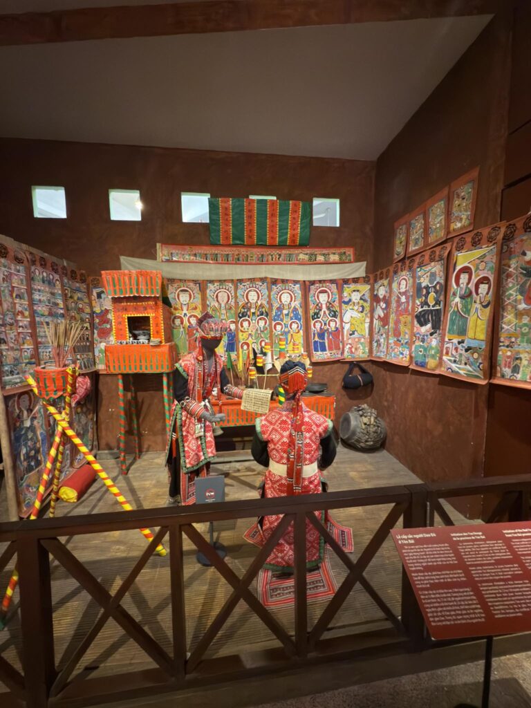 越南博物館中的紅瑤授戒儀式展示，包含祭壇、神像圖像、經幡與傳統服飾，呈現山地道教與地方神靈系統的混融。