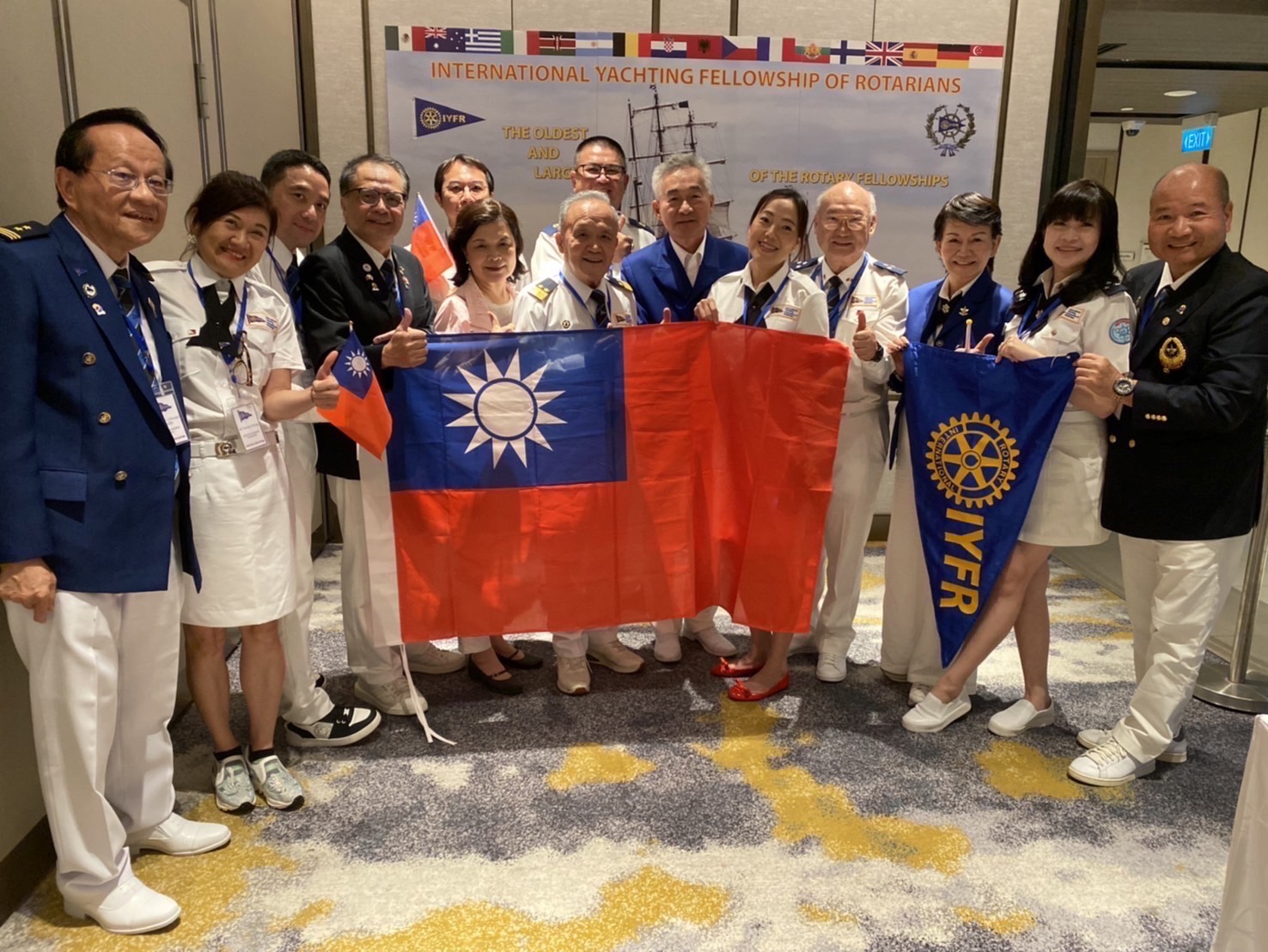 國際扶輪帆艇聯誼會成員手持中華民國國旗與 IYFR 旗幟合影
