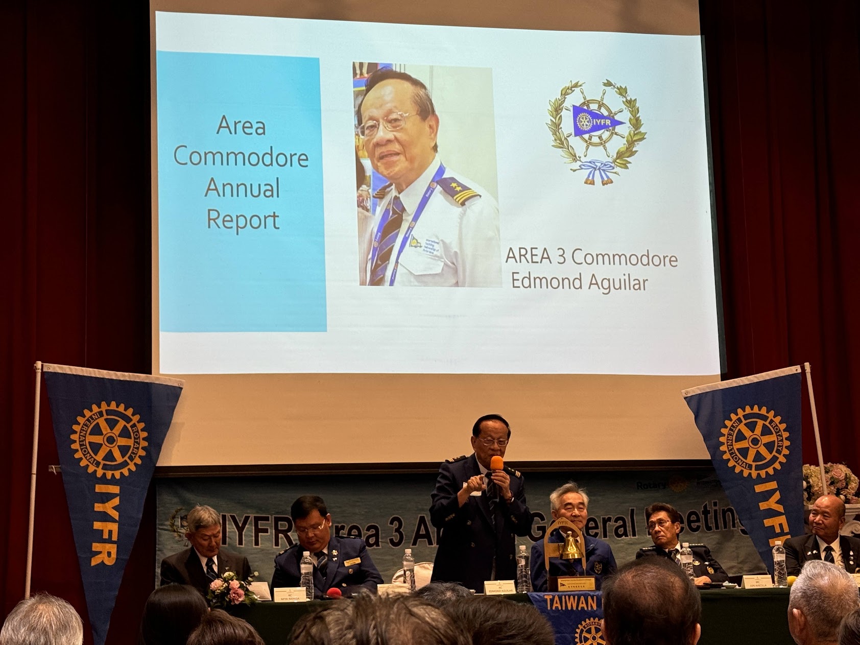IYFR Area 3 年度會員大會現場,簡報投影 Area Commodore Annual Report 與 AREA 3 Commodore Edmond Aguilar,主桌橫幅載明 IYFR Area 3 Annual General Meeting 並可見 TAIWAN 席牌