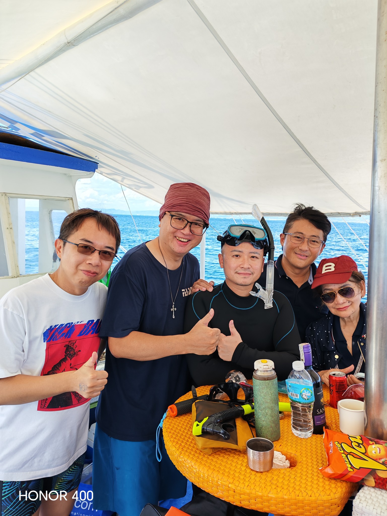 蒼藍星艦隊與菲律賓姐妹艦隊成員在船上合影，其中一人穿著浮潛防寒衣並佩戴面鏡與呼吸管